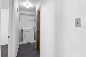 Hallway featuring dark carpet and washing machine and clothes dryer