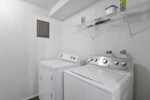 Washroom featuring electric panel and washing machine and clothes dryer