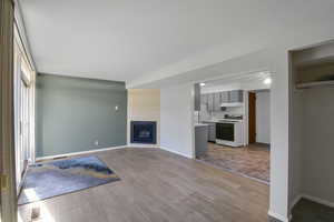 Unfurnished living room featuring a brick fireplace, light hardwood / wood-style floors, and ceiling fan