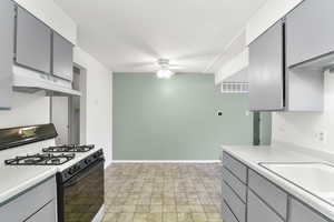 Kitchen featuring ceiling fan, gas range oven, sink, and gray cabinets