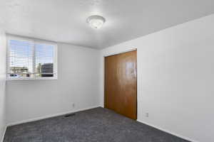 Unfurnished bedroom featuring a closet and dark colored carpet