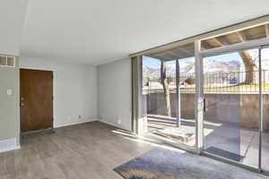 Unfurnished room with a mountain view, wood-type flooring, a wall of windows, and a healthy amount of sunlight