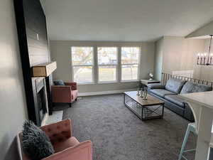 Living room featuring a wealth of natural light, a fireplace, carpet floors, and a notable chandelier