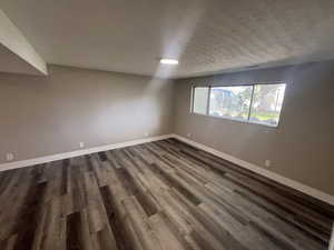 Spare room with a textured ceiling and dark wood-type flooring