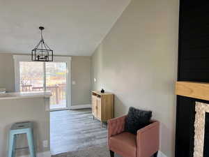 Living area featuring light hardwood / wood-style floors, lofted ceiling, and an inviting chandelier