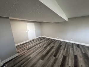 Basement featuring dark wood-type flooring and a textured ceiling