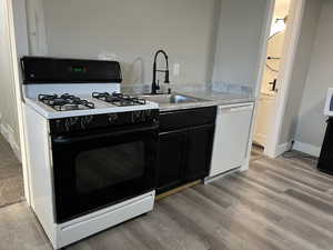 Kitchen featuring sink, light hardwood / wood-style floors, and white appliances