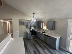 Kitchen featuring stainless steel appliances, vaulted ceiling, sink, pendant lighting, and gray cabinets