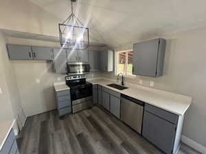 Kitchen with appliances with stainless steel finishes, sink, pendant lighting, gray cabinets, and lofted ceiling