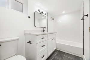 Full bathroom featuring tile patterned floors, vanity, toilet, and tiled shower / bath combo