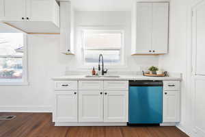 Kitchen with light stone countertops, white cabinets, sink, dishwasher, and dark hardwood / wood-style floors