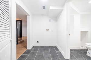 Laundry room with hookup for an electric dryer, hookup for a washing machine, and dark tile patterned flooring