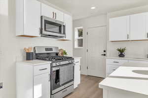 Kitchen with white cabinets, light wood-type flooring, and stainless steel appliances