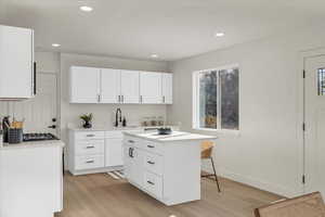 Kitchen featuring white cabinets, a center island, light hardwood / wood-style flooring, and sink