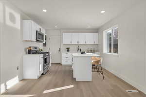 Kitchen with a center island, white cabinetry, a breakfast bar area, and appliances with stainless steel finishes