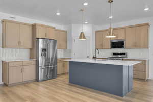 Kitchen featuring a kitchen island with sink, appliances with stainless steel finishes, light brown cabinetry, and sink