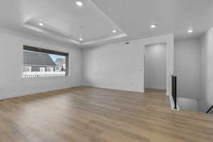 Unfurnished living room featuring light hardwood / wood-style flooring, a raised ceiling, and a textured ceiling