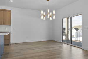 Unfurnished dining area with a notable chandelier and light hardwood / wood-style floors