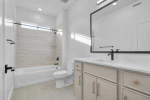 Full bathroom featuring vanity, tiled shower / bath, tile patterned floors, and toilet