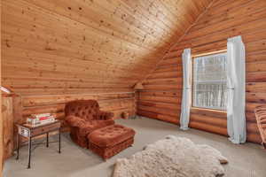 Living area featuring lofted ceiling, wood ceiling, rustic walls, and light carpet