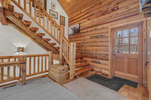 Foyer entrance featuring log walls, hardwood / wood-style flooring, lofted ceiling, and wooden ceiling