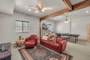 Carpeted living room with ceiling fan and beam ceiling