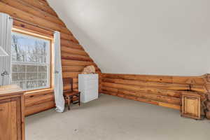 Additional living space featuring log walls, light carpet, and vaulted ceiling