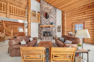 Carpeted living room featuring a wood stove, high vaulted ceiling, rustic walls, and wooden ceiling