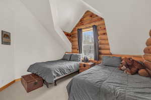 Carpeted bedroom with log walls and lofted ceiling