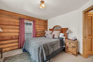 Carpeted bedroom featuring rustic walls