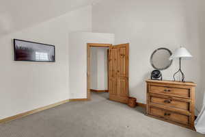 Unfurnished bedroom featuring light carpet and vaulted ceiling