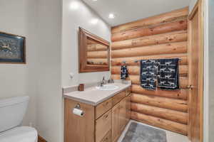 Bathroom featuring rustic walls, vanity, and toilet