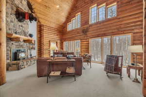 Carpeted living room featuring rustic walls, high vaulted ceiling, wooden ceiling, and a wood stove