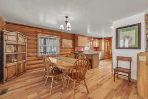 Dining area with light wood-type flooring, an inviting chandelier, rustic walls, and sink