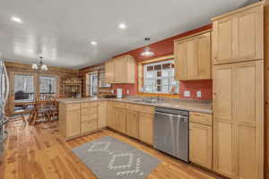 Kitchen with dishwasher, light brown cabinetry, kitchen peninsula, and hanging light fixtures