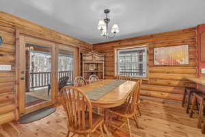 Dining room with light hardwood / wood-style floors, rustic walls, and a chandelier