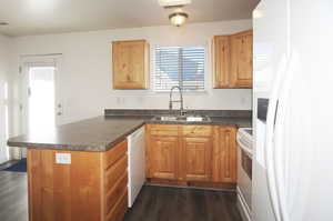 Kitchen featuring dark hardwood / wood-style floors, sink, white appliances, and kitchen peninsula