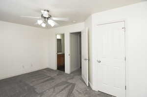 Unfurnished bedroom featuring connected bathroom, ceiling fan, sink, and dark carpet