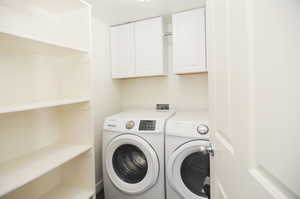 Laundry area with separate washer and dryer and cabinets