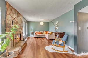 Living room featuring a fireplace, a textured ceiling, and light hardwood / wood-style floors