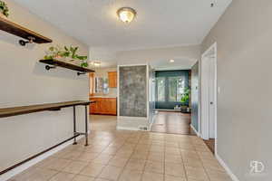 Hallway featuring sink, light tile patterned floors, and a textured ceiling