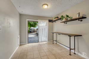 Entryway with a textured ceiling and light tile patterned flooring