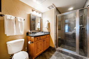 Bathroom featuring tile patterned flooring, vanity, toilet, and walk in shower