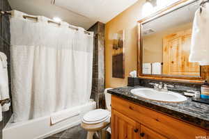 Full bathroom with tile patterned flooring, shower / bath combo, vanity, and toilet