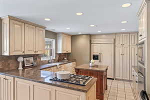 Kitchen featuring kitchen peninsula, tasteful backsplash, light tile patterned flooring, and sink