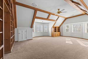 Bonus room featuring a textured ceiling, carpet floors, ceiling fan, and lofted ceiling