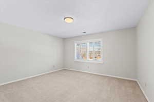 Unfurnished room with light colored carpet and a textured ceiling