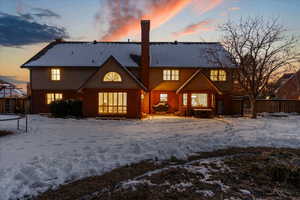 Snow covered rear of property with a trampoline