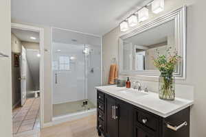 Bathroom with tile patterned floors, a shower with door, and vanity