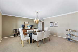 Carpeted dining area featuring ornamental molding and a chandelier